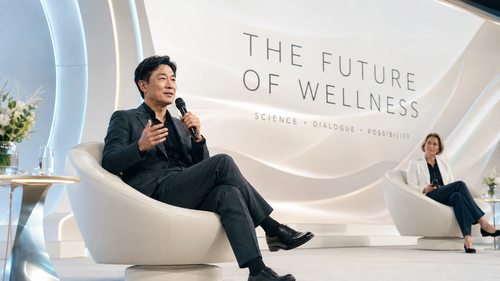 概念国际健康论坛，一位虚构创业者形象在英文主题背景前坐着交流。